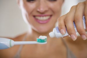 woman putting toothpaste on toothbrush